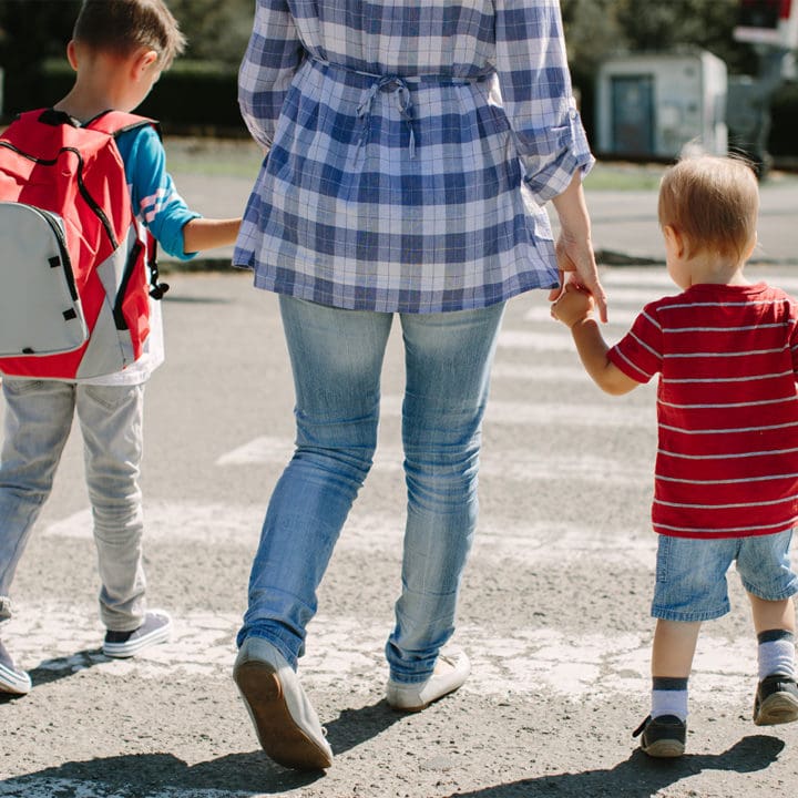 A mother walking two children across the street