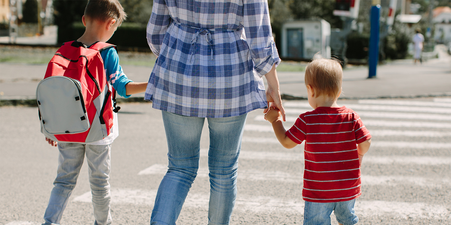 A mother walking two children across the street