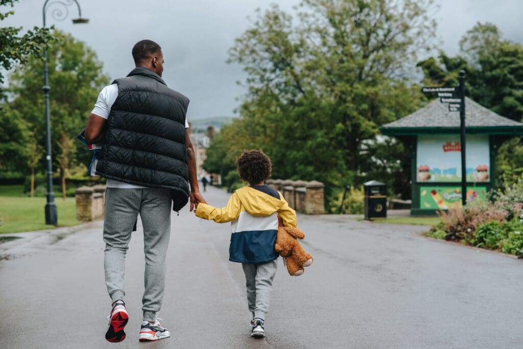 a man and child hold hands as they walk down the street