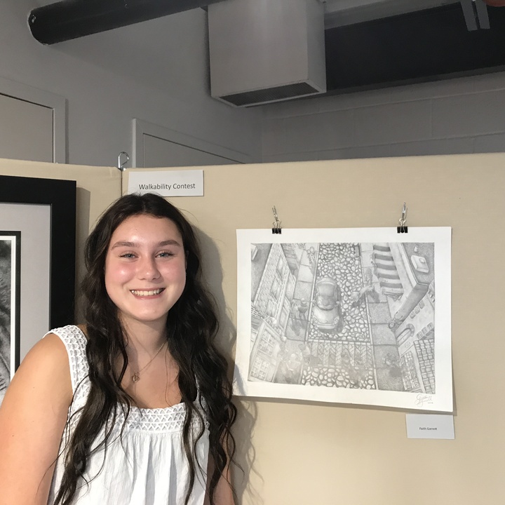 photo of Faith in front of her drawing of a cityscape