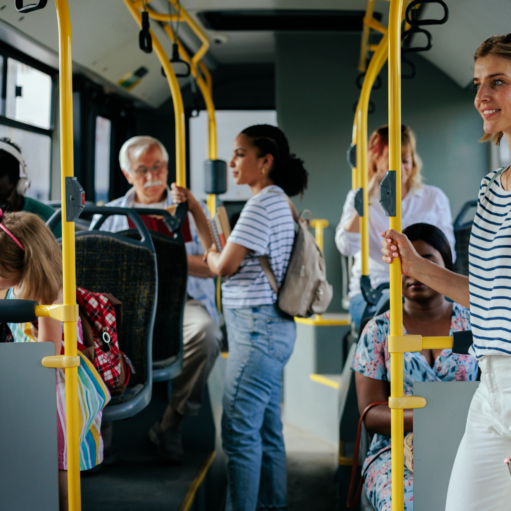 Photo of people standing and sitting while riding a bus