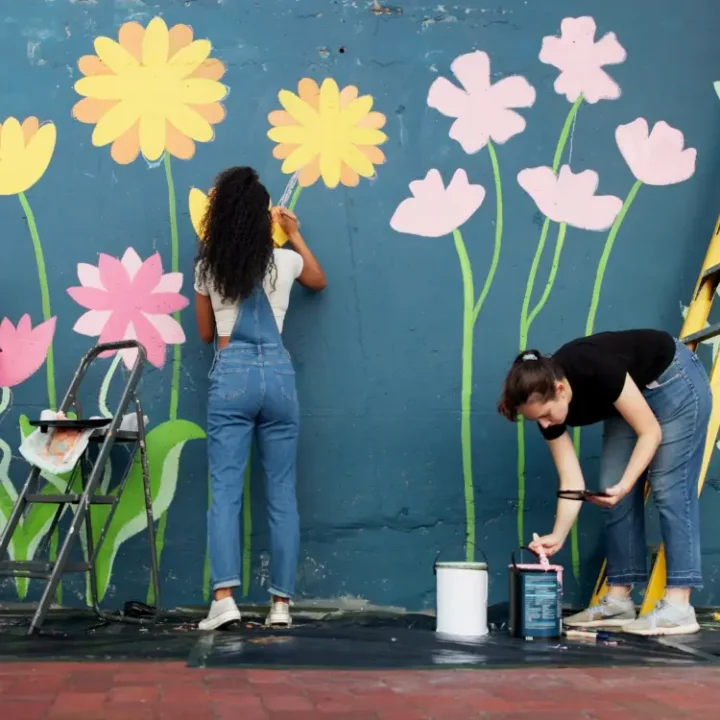 people painting a mural of flowers