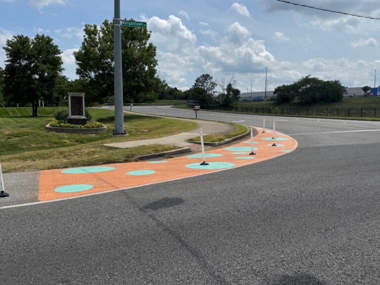 a crosswalk at an intersection with a painted bike and walking path and delineators