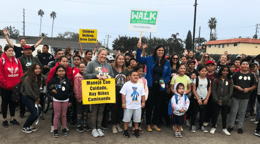 people stand with signs for a walk to school day