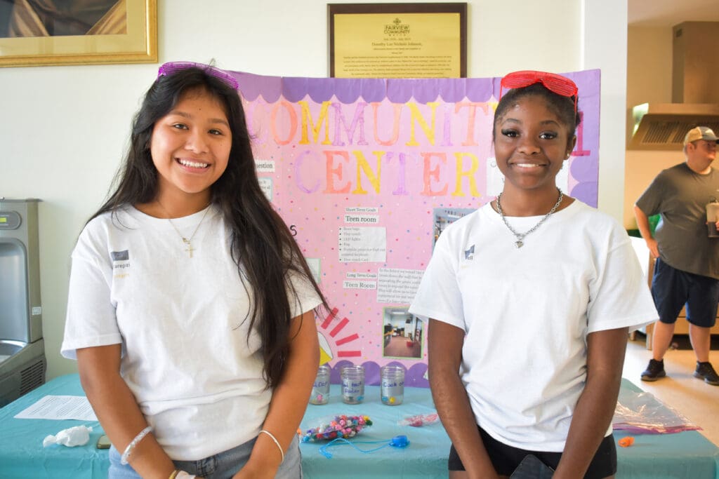 two interns present at walk fairview day in front of a bright poster board