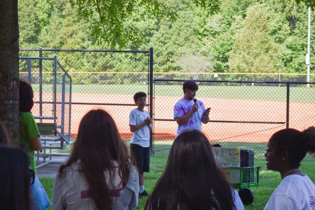 two interns present at walk fairview day in front of a sports field