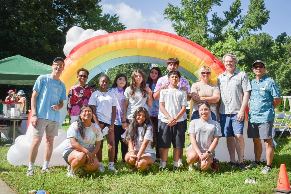 youth action interns gather with local leaders under a rainbow arch for a photo